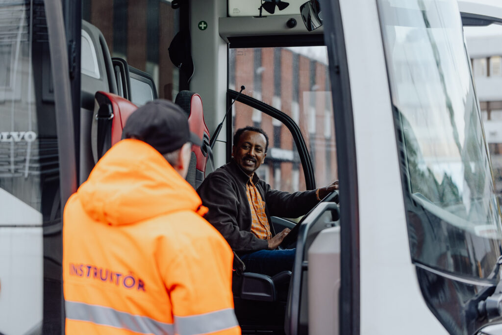 Instruktör diskuterar med en busselev invid en buss
