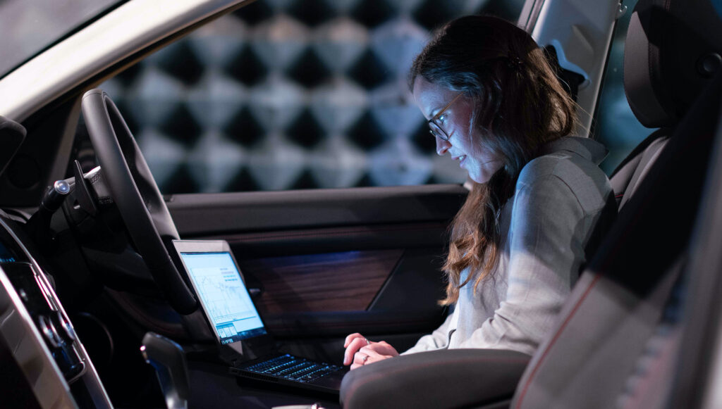 En kvinnlig mjukvaruutvecklare arbetar med sin dator i en bil