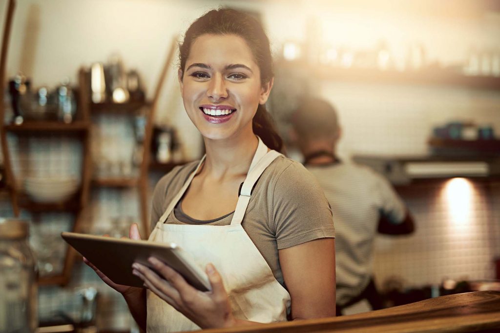 Kvinna står på ett cafe med en iPad i handen