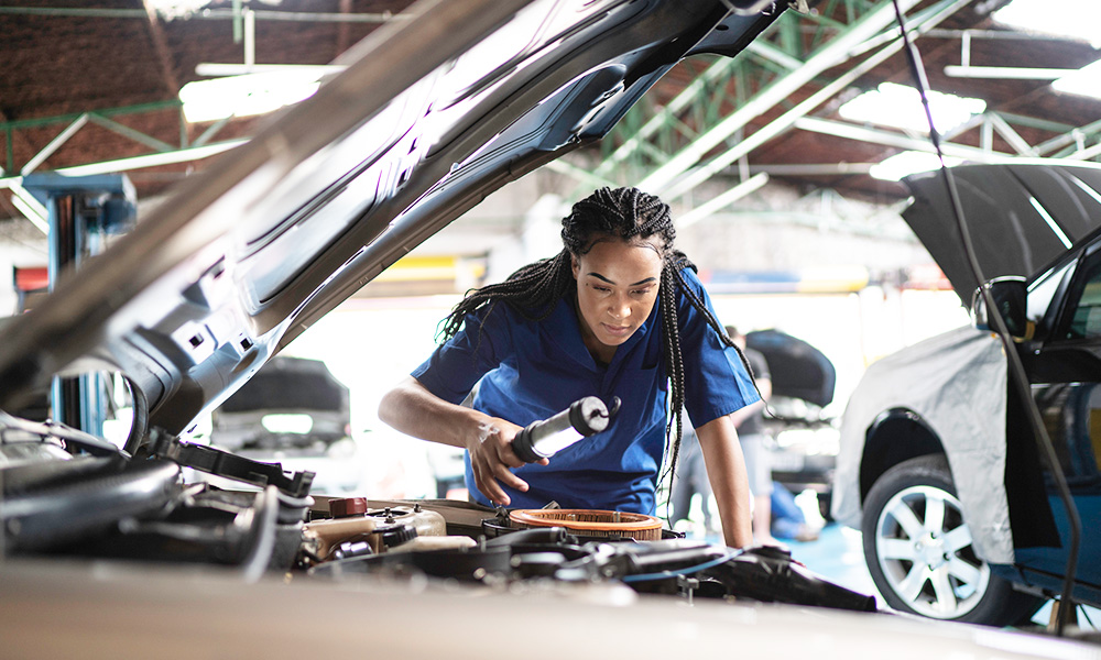 Kvinna reparerar bil i en bilverkstad