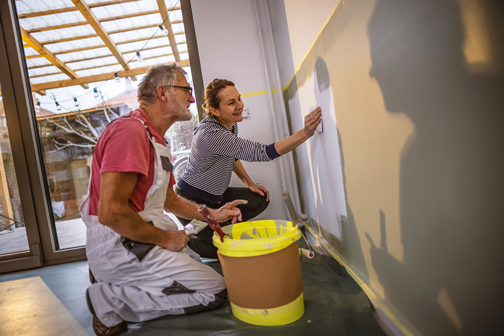 Lärare instruerar elev inom måleri vid en vägg