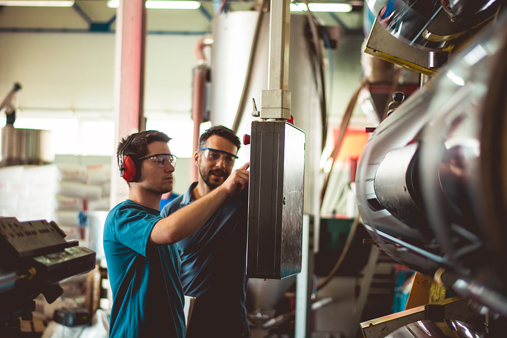 Två personer står vid en maskin